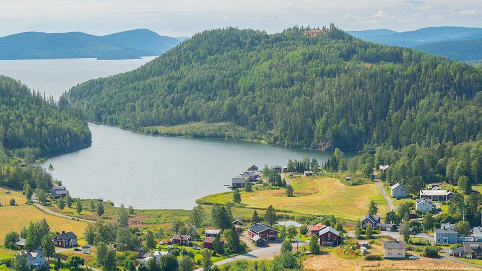 Utsikt &ouml;ver vacker by med hus, skog, vatten, v&aring;tmark och &aring;kermark. H&ouml;ga Kusten, H&auml;ggvik, &Aring;ngermanland.